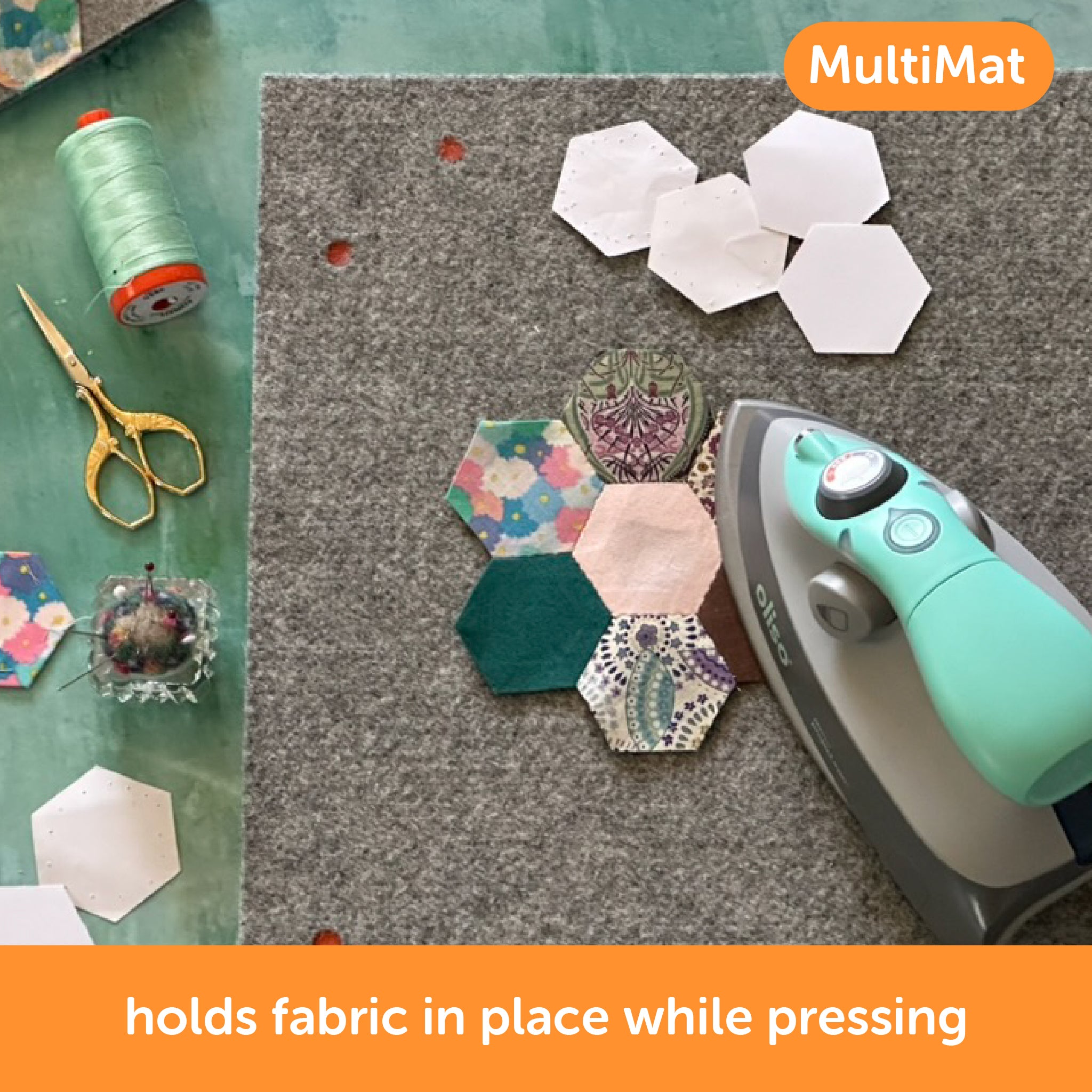 Content description ="Oliso M3Pro mini project iron in aqua color pressing a paper piecing project on a MultiMat wool mat. The MultiMat holds fabric in place while pressing.">