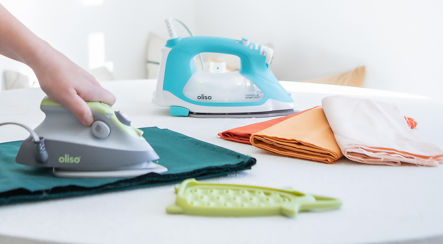 Oliso Auto-Lift Smart Iron in Turquoise & M3Pro Project Iron in Pistachio, ideal for pressing, quilting & sewing.
