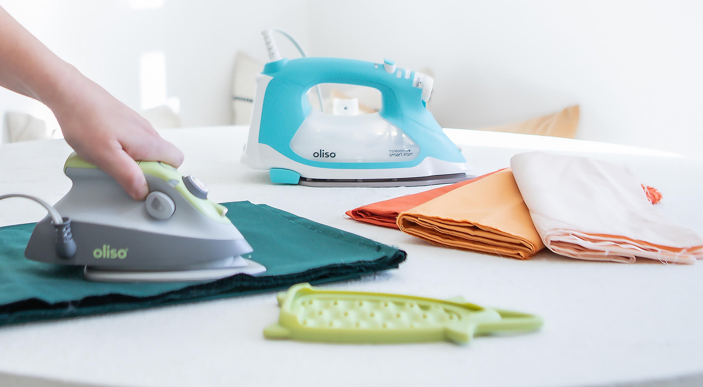 Oliso Auto-Lift Smart Iron in Turquoise & M3Pro Project Iron in Pistachio, ideal for pressing, quilting & sewing.