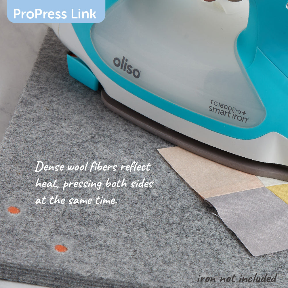 Oliso Smart Iron  pressing quilt squares on the felt mat, the dense fibers reflect heat pressing both sides at once.